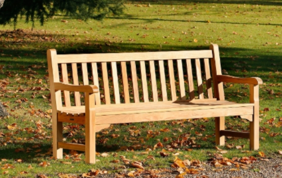 A teak bench in a backyard.