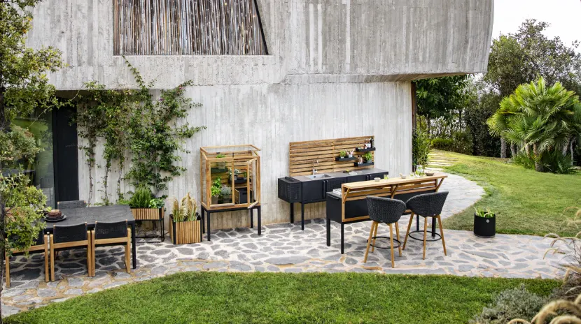 An outdoor kitchen with a sink, an eat-in counter with two stools, and a dining table with some chairs.