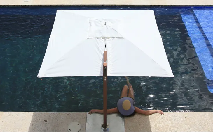 A woman sitting in a pool under an umbrella.