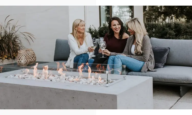 Three woman sitting on a sofa with wine glasses.