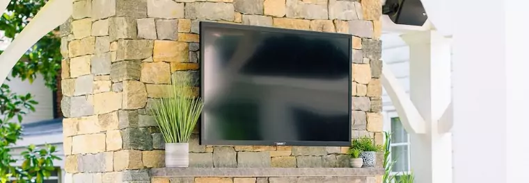 An outdoor TV mounted on a brick wall.