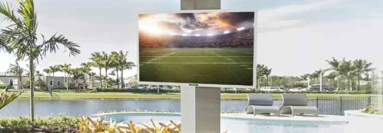 An outdoor TV mounted on a column by a pool.