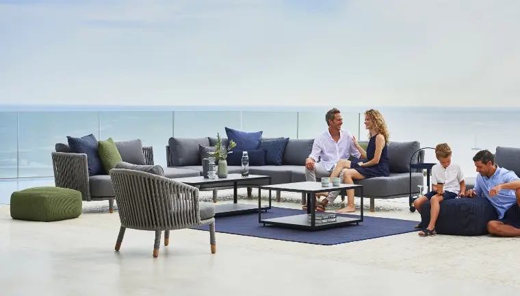 A man and woman sitting on a sectional while a boy and a man sit on a bean bag on the floor.