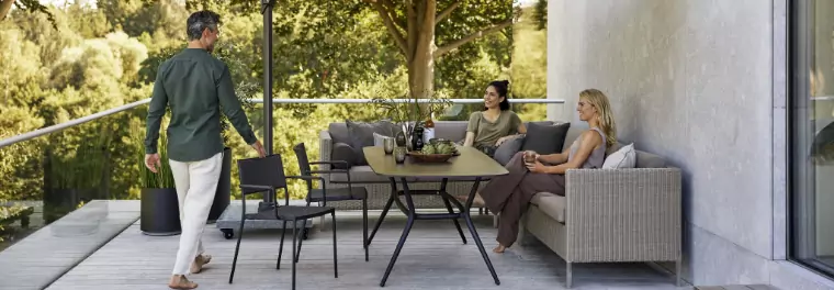 Two women sitting on a sofa while a man walks towards them.