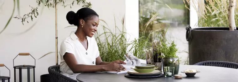 A woman reading a magazine while sitting on a table.