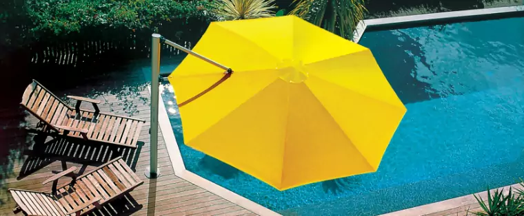 A large yellow umbrella by a pool.