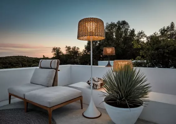A pedestal lamp on a rooftop sitting area on a sunset.