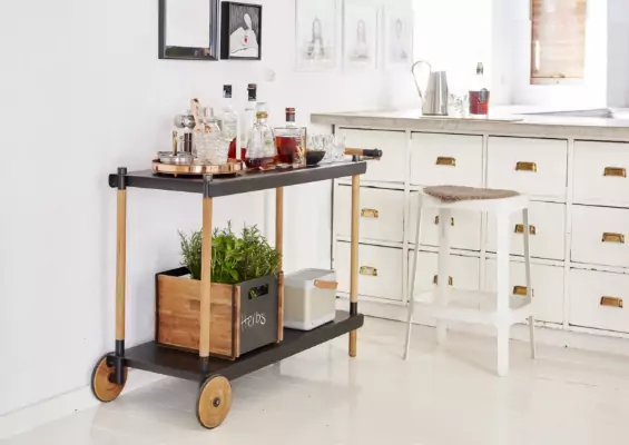 A serve cart with various bottles of liquor on top.