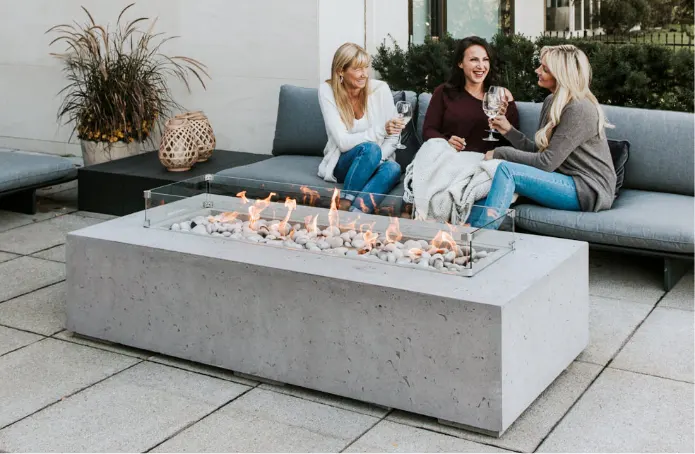 A large concrete fire table in front of a sofa where three women are sitting.