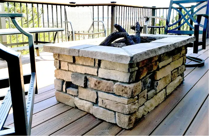 A rectangular stone fire table surrounded by some chairs.