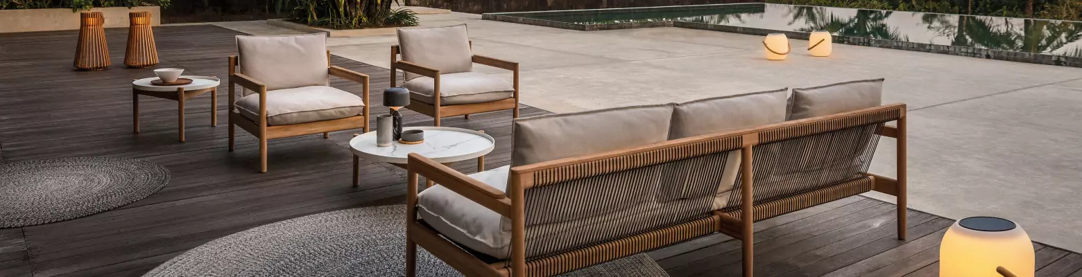 A sitting area with a sofa and two chairs with various lanterns surrounding them.