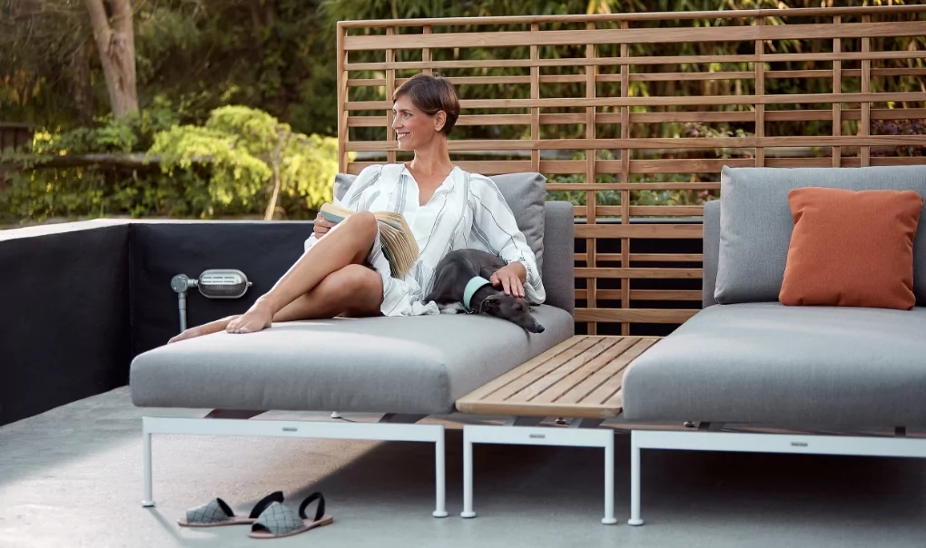 A woman laying on a chaise lounger reading a book.