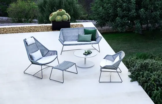 A rooftop sitting area with a large chair, a small accent chair, and a loveseat with a small round table in the center.