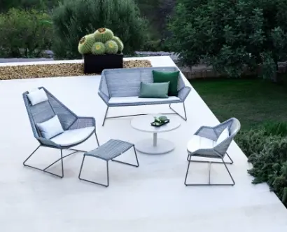 A rooftop sitting area with a large chair, a small accent chair, and a loveseat with a small round table in the center.