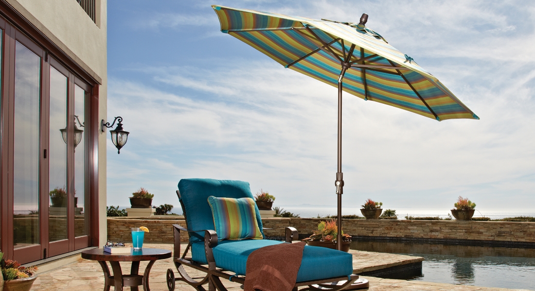 A large umbrella covering a lounger by a pool.