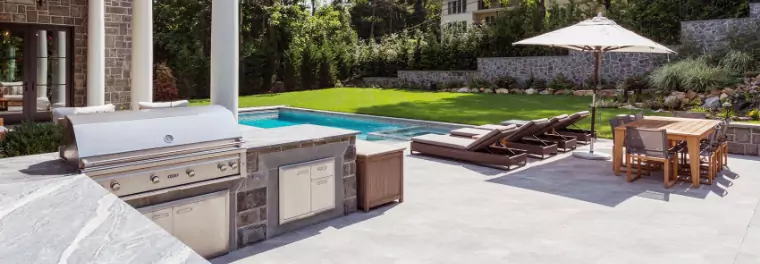 An outdoor kitchen by a pool.