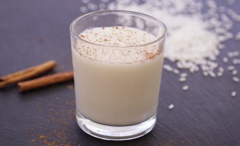 A glass of Coconut Horchata, a white drink with cinnamon powder