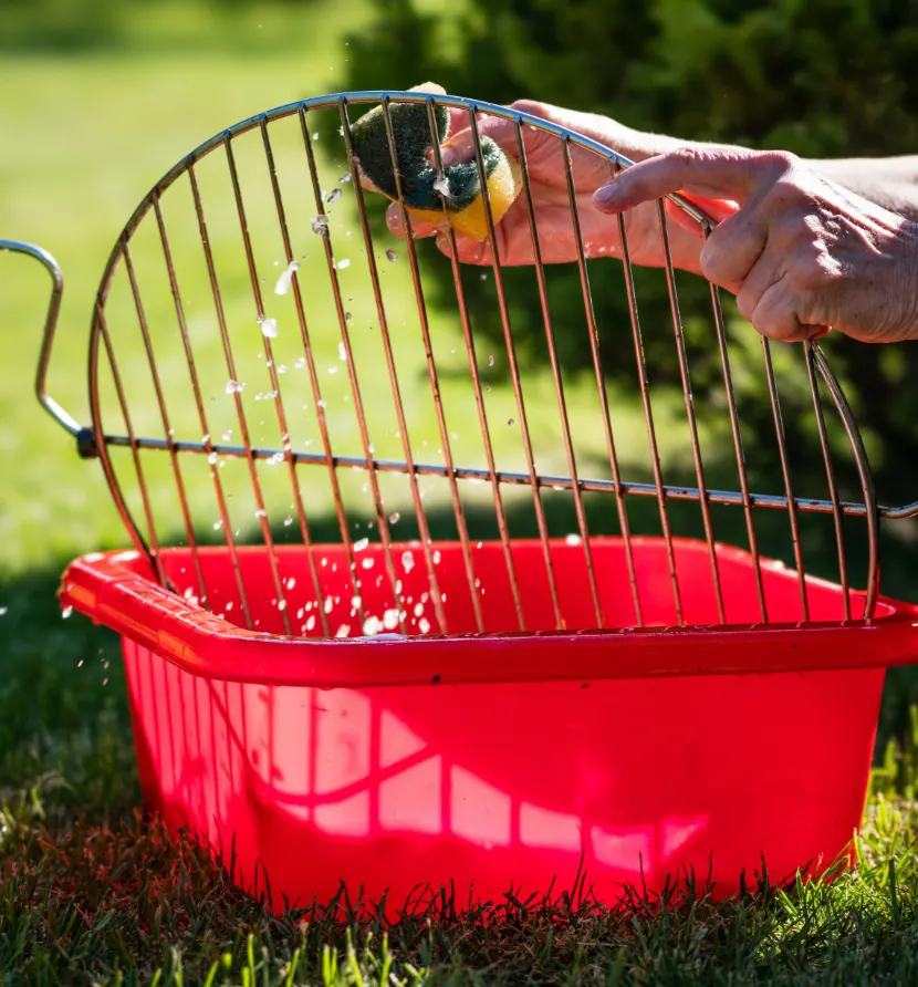 Someone cleaning a grill with a sponge and some soapy water.