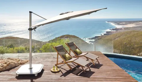 A large cantilever umbrella covering two chaise loungers that are in front of a pool.