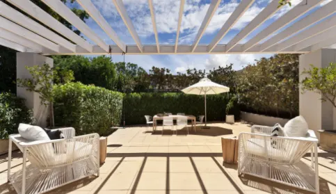 A patio with two chairs and a table with six chairs and a small umbrella.