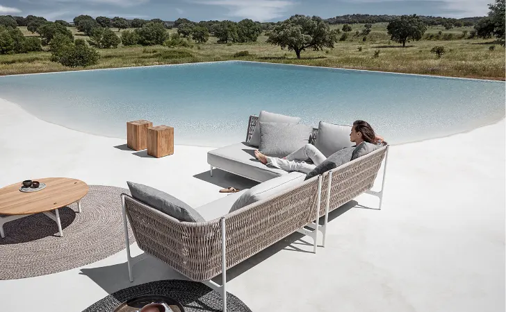 A woman sitting on a sofa by an infinity pool.