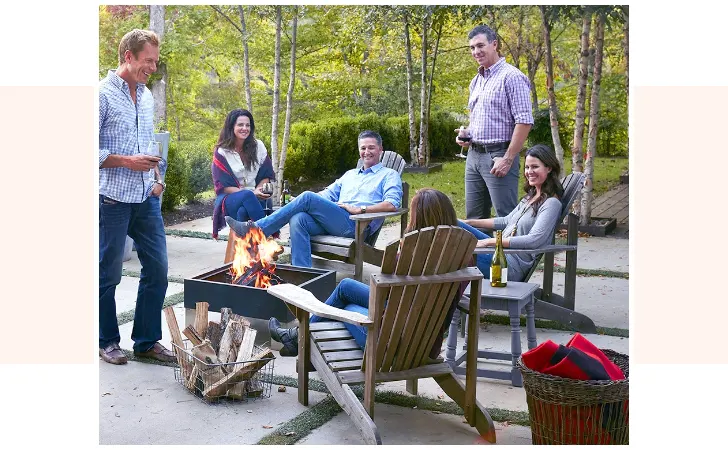 A group of people having a good time by a square fire pit.