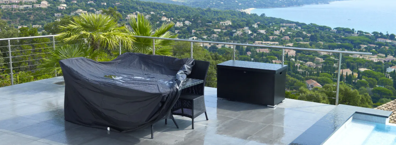 A table with a few chairs under a cover.