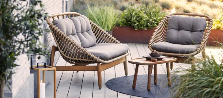 Two chairs with a small table in front of them on a deck.