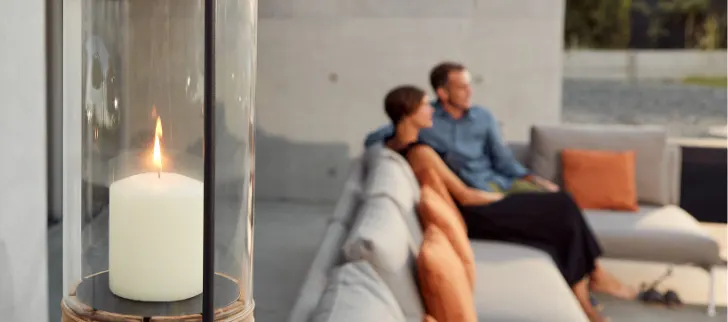A candle is burning while a couple sits on a sofa in the background.