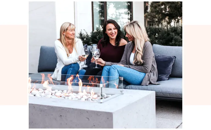 Three women sitting on a sofa drinking some wine.