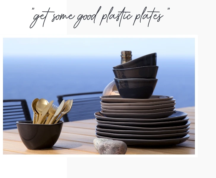 Plates stacked on each other on a table and a small bowl with cutlery inside.