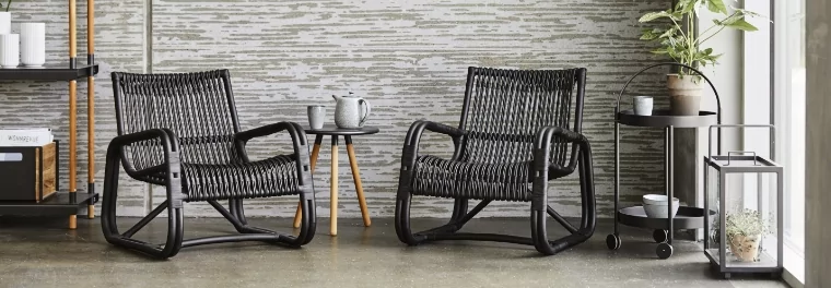 Two black woven chairs with a small table in between.