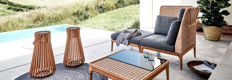 A loveseat with a table next to it and two lanterns.