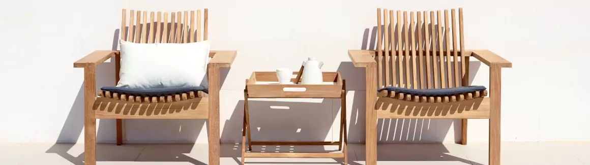 Two teak chairs with a teak table in between.
