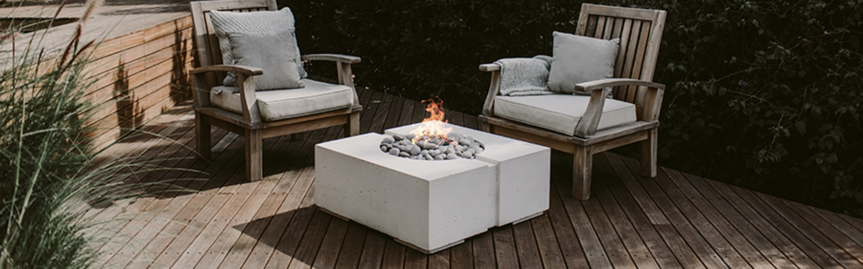 Two chairs in front of a concrete square fire pit.