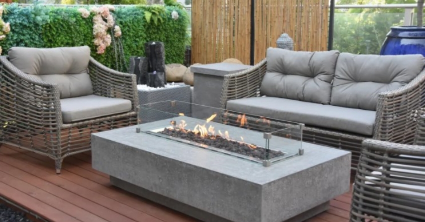 A rectangular concrete fire table in between a sofa and two chairs.
