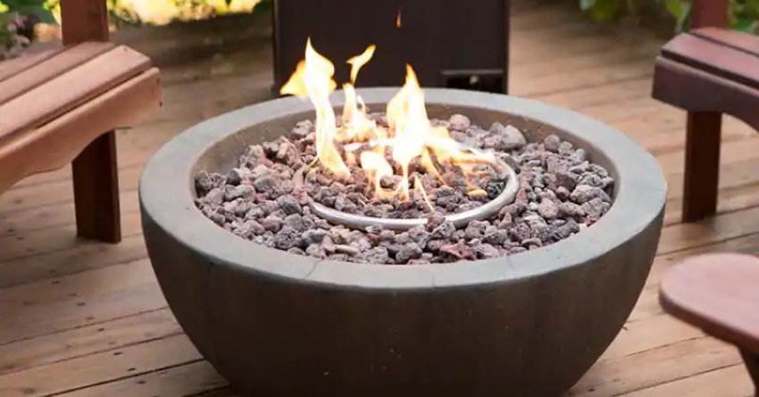 A round fire pit filled with fire rocks and a coil burning.