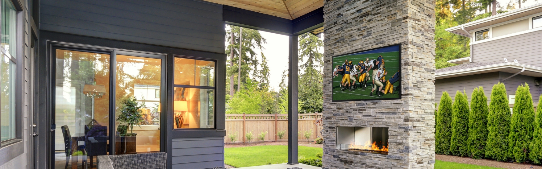 An outdoor TV hanging from an fireplace in a patio.