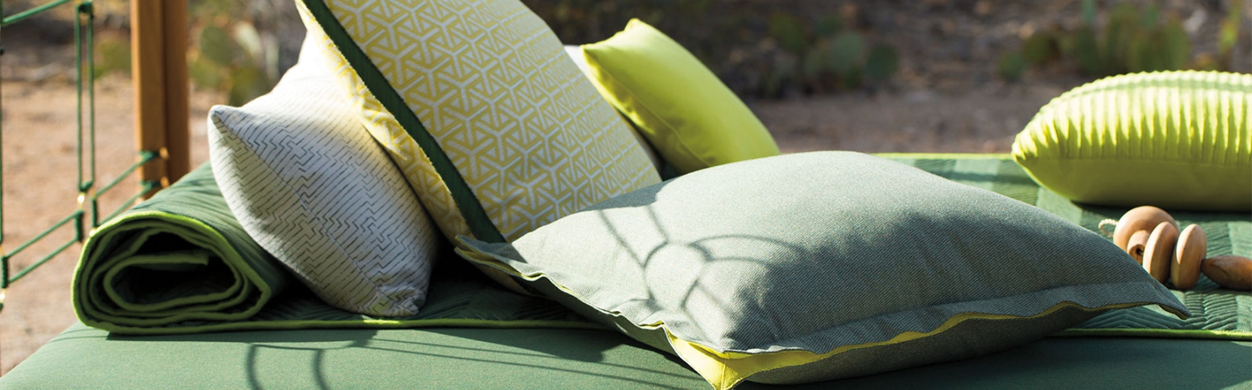 Different shades of green pillows on an outdoor daybed