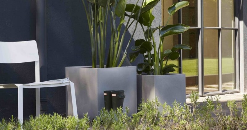 Two square planters of various sizes next to a chair.