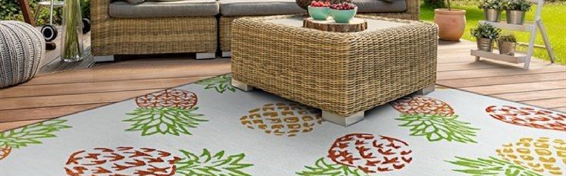 An outdoor sitting area with some wicker furniture on top of a rug with pineapple patterns.